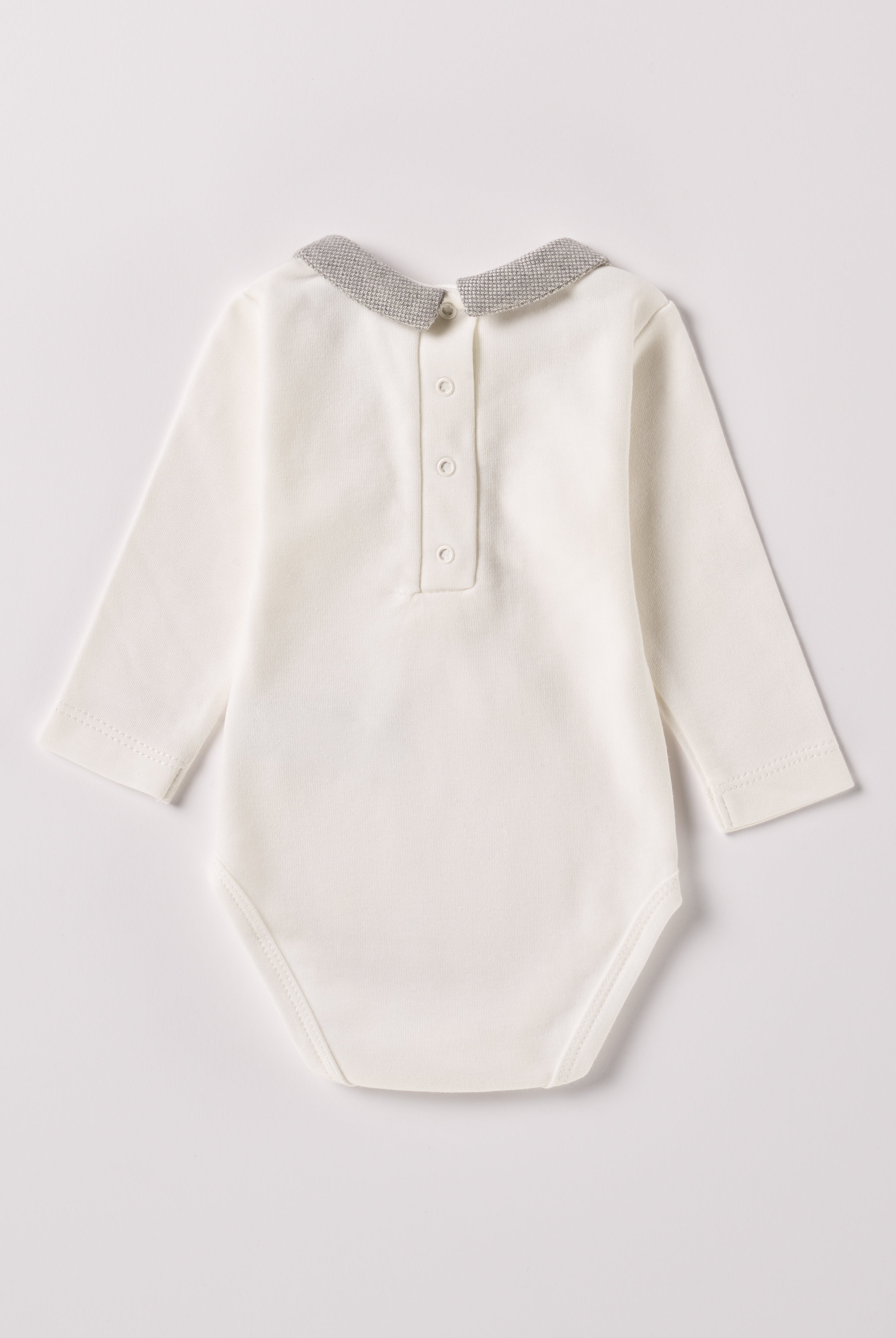 Der langarmige Body, gefertigt aus 100% Baumwolle, hat eine perfekte Passform. Kundinnen und Kunden vertrauen auf unseren Schnitt, da die flachen Knöpfe an der Rückseite ein unkompliziertes und schnelles Anziehen ermöglichen. Die "flanellartige" Innenseite wurde speziell für zarte Kinderhaut konzipiert und bietet ein besonders sanftes Trageerlebnis. Ein großer Vorteil der flanellartigen Innenseite ist, dass die Kinder weniger schwitzen. Der Kragen verleiht dem Body ein edles Design.