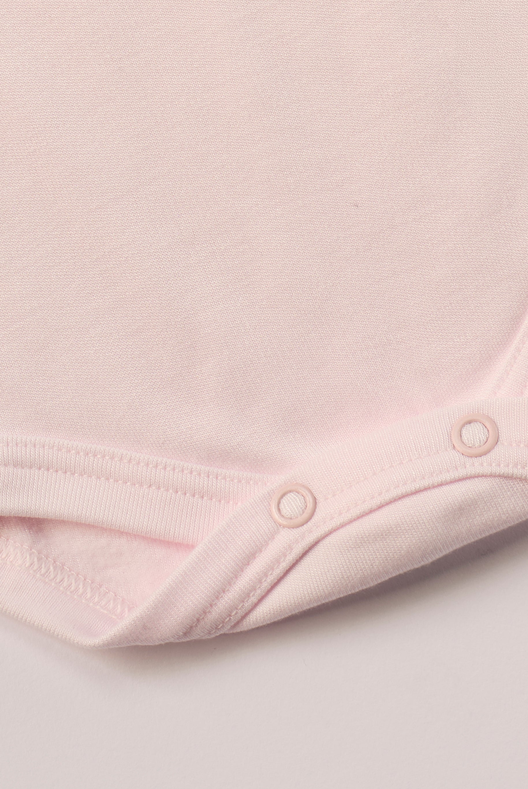 Für besonders sensible Babyhaut. Dieser rosa Amerciano Body besteht aus hochwertiger Bambusviskose — einem Material, das für seine seidige Weichheit, hohe Atmungsaktivität und temperaturausgleichenden Eigenschaften bekannt ist. Sanft zur Haut, funktional im Alltag.