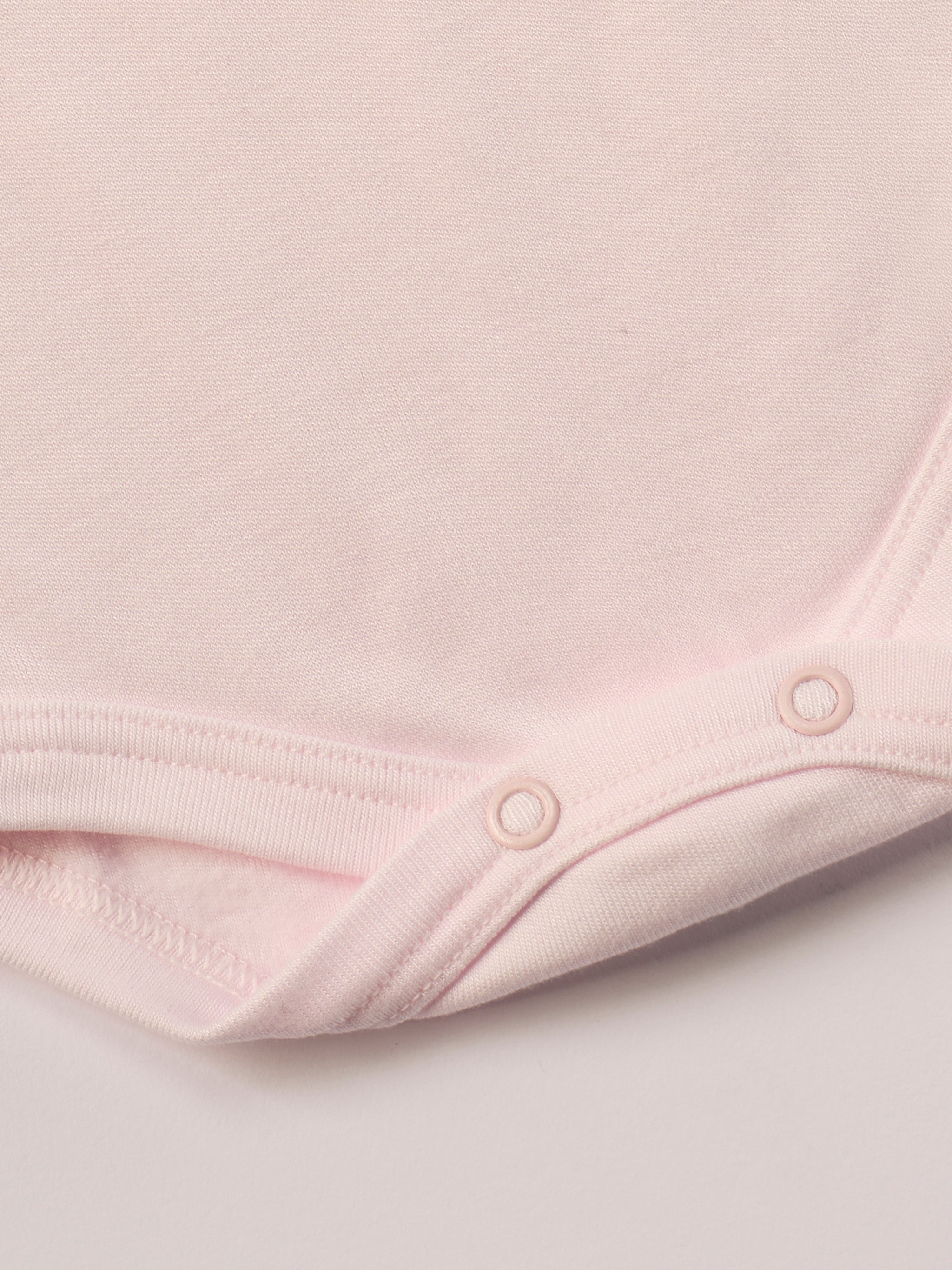 Für besonders sensible Babyhaut. Dieser rosa Amerciano Body besteht aus hochwertiger Bambusviskose — einem Material, das für seine seidige Weichheit, hohe Atmungsaktivität und temperaturausgleichenden Eigenschaften bekannt ist. Sanft zur Haut, funktional im Alltag.