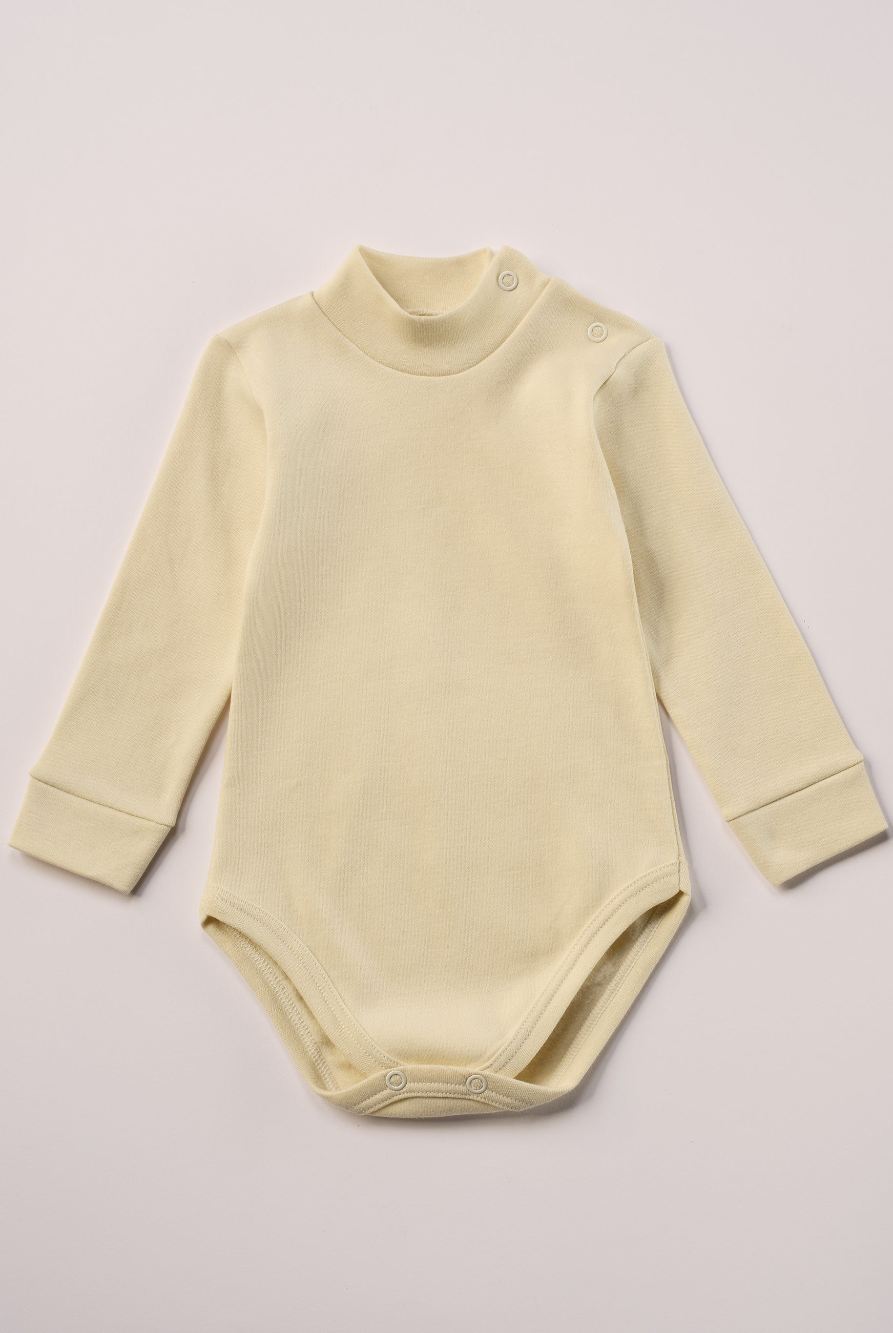 Dieser beige Stehkragenbody besteht aus hochwertiger, sorgfältig veredelter organischer Baumwolle. Die Stoffe sind sanft gefärbt und gebleicht unter Einhaltung strenger EU-Standards. Die nickelfreien Druckknöpfe an der Schulterpartie machen das An- und Ausziehen unkompliziert und schnell.
Innen sorgt die weich angeraute Oberfläche für angenehme Wärme, Feuchtigkeitsaufnahme und ein sanftes Hautgefühl. Der schützende Stehkragen hält den empfindlichen Halsbereich warm und reduziert Zugluft.