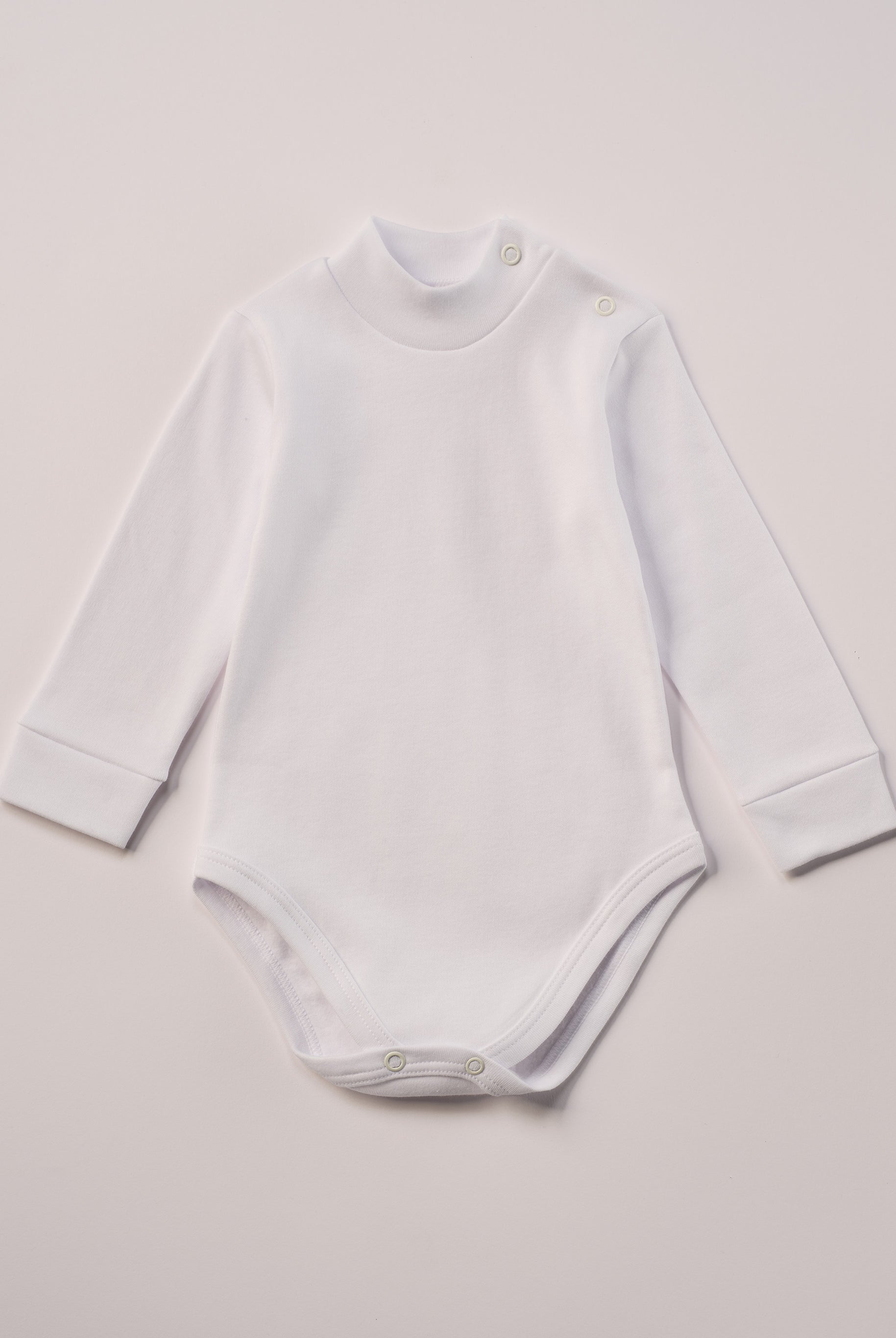 Dieser weiße Stehkragenbody besteht aus hochwertiger, sorgfältig veredelter Baumwolle. Die Stoffe sind sanft gefärbt und gebleicht unter Einhaltung strenger EU-Standards. Die nickelfreien Druckknöpfe an der Schulterpartie machen das An- und Ausziehen unkompliziert und schnell.
Innen sorgt die weich angeraute Oberfläche für angenehme Wärme, Feuchtigkeitsaufnahme und ein sanftes Hautgefühl. Der schützende Stehkragen hält den empfindlichen Halsbereich warm und reduziert Zugluft – ideal für Alltag oder Kita.