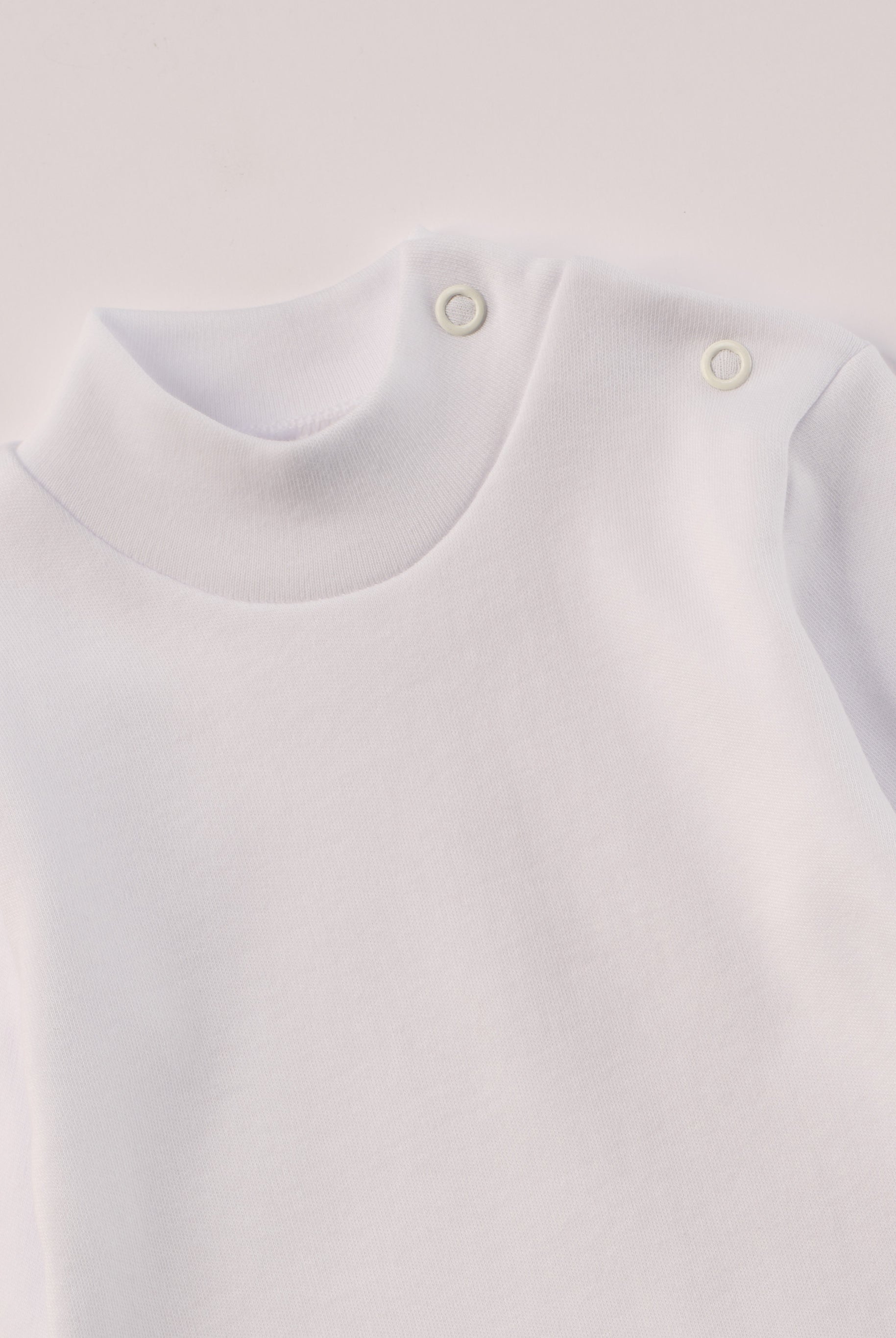 Dieser weiße Stehkragenbody besteht aus hochwertiger, sorgfältig veredelter Baumwolle. Die Stoffe sind sanft gefärbt und gebleicht unter Einhaltung strenger EU-Standards. Die nickelfreien Druckknöpfe an der Schulterpartie machen das An- und Ausziehen unkompliziert und schnell.
Innen sorgt die weich angeraute Oberfläche für angenehme Wärme, Feuchtigkeitsaufnahme und ein sanftes Hautgefühl. Der schützende Stehkragen hält den empfindlichen Halsbereich warm und reduziert Zugluft – ideal für Alltag oder Kita.