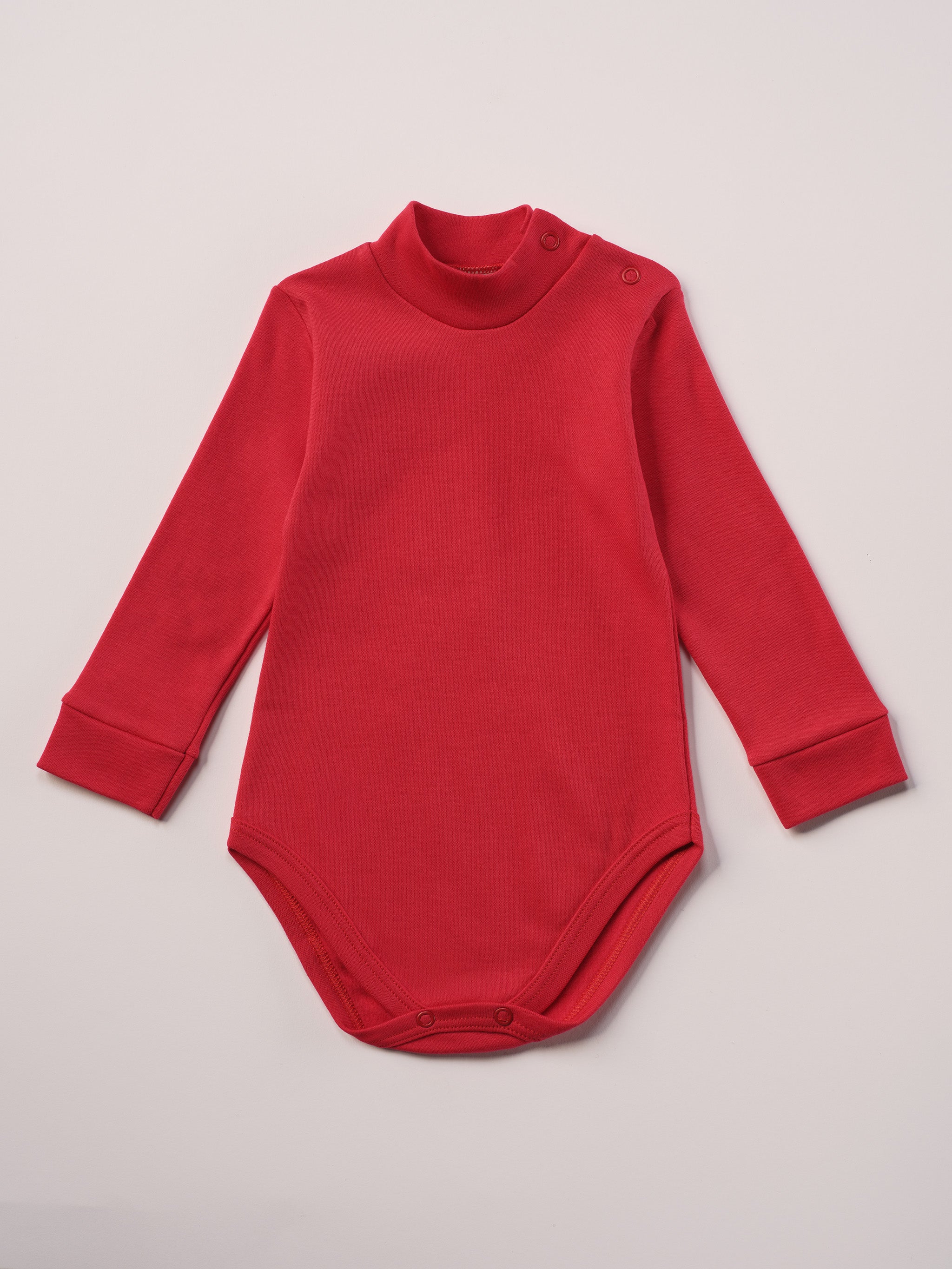 Dieser rote Stehkragenbody besteht aus hochwertiger, sorgfältig veredelter organischer Baumwolle. Die Stoffe sind sanft gefärbt und gebleicht unter Einhaltung strenger EU-Standards. Die nickelfreien Druckknöpfe an der Schulterpartie machen das An- und Ausziehen unkompliziert und schnell.
Innen sorgt die weich angeraute Oberfläche für angenehme Wärme, Feuchtigkeitsaufnahme und ein sanftes Hautgefühl. Der schützende Stehkragen hält den empfindlichen Halsbereich warm und reduziert Zugluft.