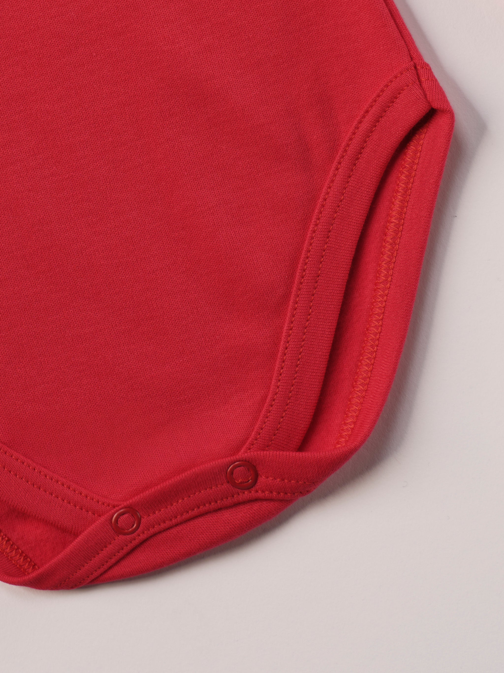 Dieser rote Stehkragenbody besteht aus hochwertiger, sorgfältig veredelter organischer Baumwolle. Die Stoffe sind sanft gefärbt und gebleicht unter Einhaltung strenger EU-Standards. Die nickelfreien Druckknöpfe an der Schulterpartie machen das An- und Ausziehen unkompliziert und schnell.
Innen sorgt die weich angeraute Oberfläche für angenehme Wärme, Feuchtigkeitsaufnahme und ein sanftes Hautgefühl. Der schützende Stehkragen hält den empfindlichen Halsbereich warm und reduziert Zugluft.