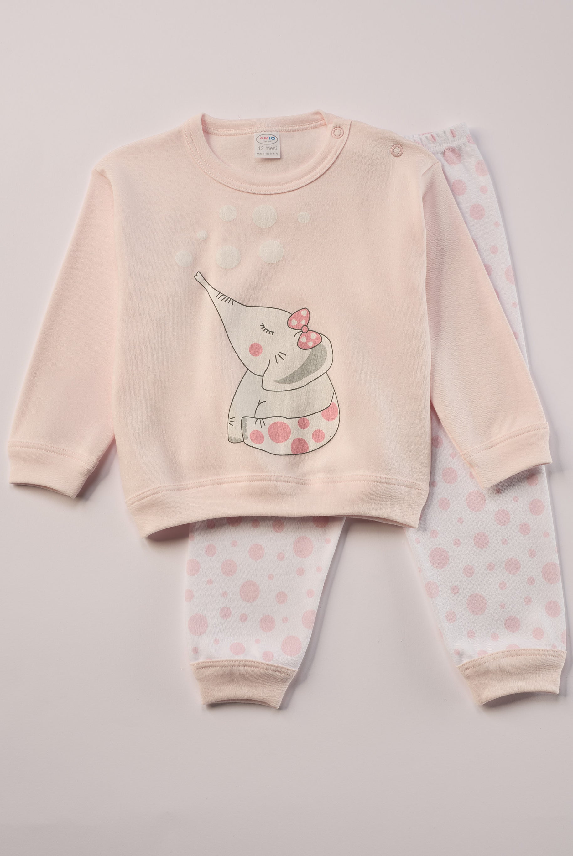Für ruhige Nächte und gemütliche Morgenstunden. Dieser Pyjama für Babys & Kinder von 12 Monaten bis 3 Jahren besteht aus hochwertiger organischer Baumwolle und ist innen sanft angeraut. Das weiche Innenflanell sorgt für ein besonders angenehmes Tragegefühl und hält warm, ohne zu überhitzen. Gefertigt in Italien aus Stoffen italienischer Produktion – mit einem klaren Anspruch an Qualität, Langlebigkeit und kindgerechtem Komfort. Design mit rosa Elefanten-Motiv auf dem Oberteil und rosa gepunkteter Hose.