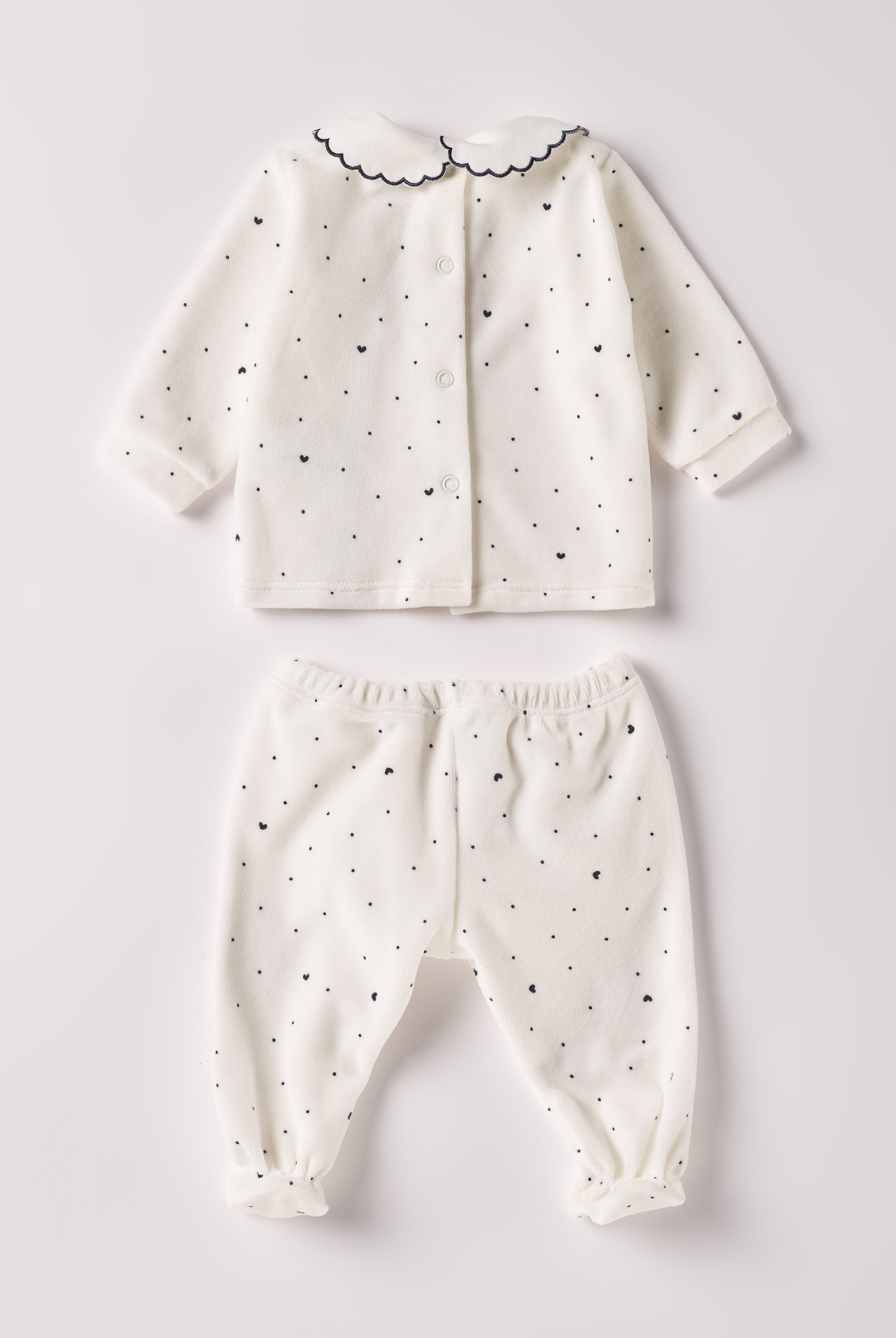 Der weiche und wärmespendende Zweiteiler von AMIO Firenze mit besticktem Kragen und eingewebten Herzen ist der perfekte Begleiter für den Alltag in der kalten Jahreszeit. Die echten Perlmuttknöpfe auf der Vorderseite veredeln den Look. Maximaler Tragekomfort, gepaart mit einer herausragenden Passform aus Samt (Ciniglia). Das Modell hat einen praktischen Schnitt, um etwa die Windel schnell und unkompliziert wechseln zu können. Das Set aus Oberteil und Hose ist vielseitig kombinierbar.