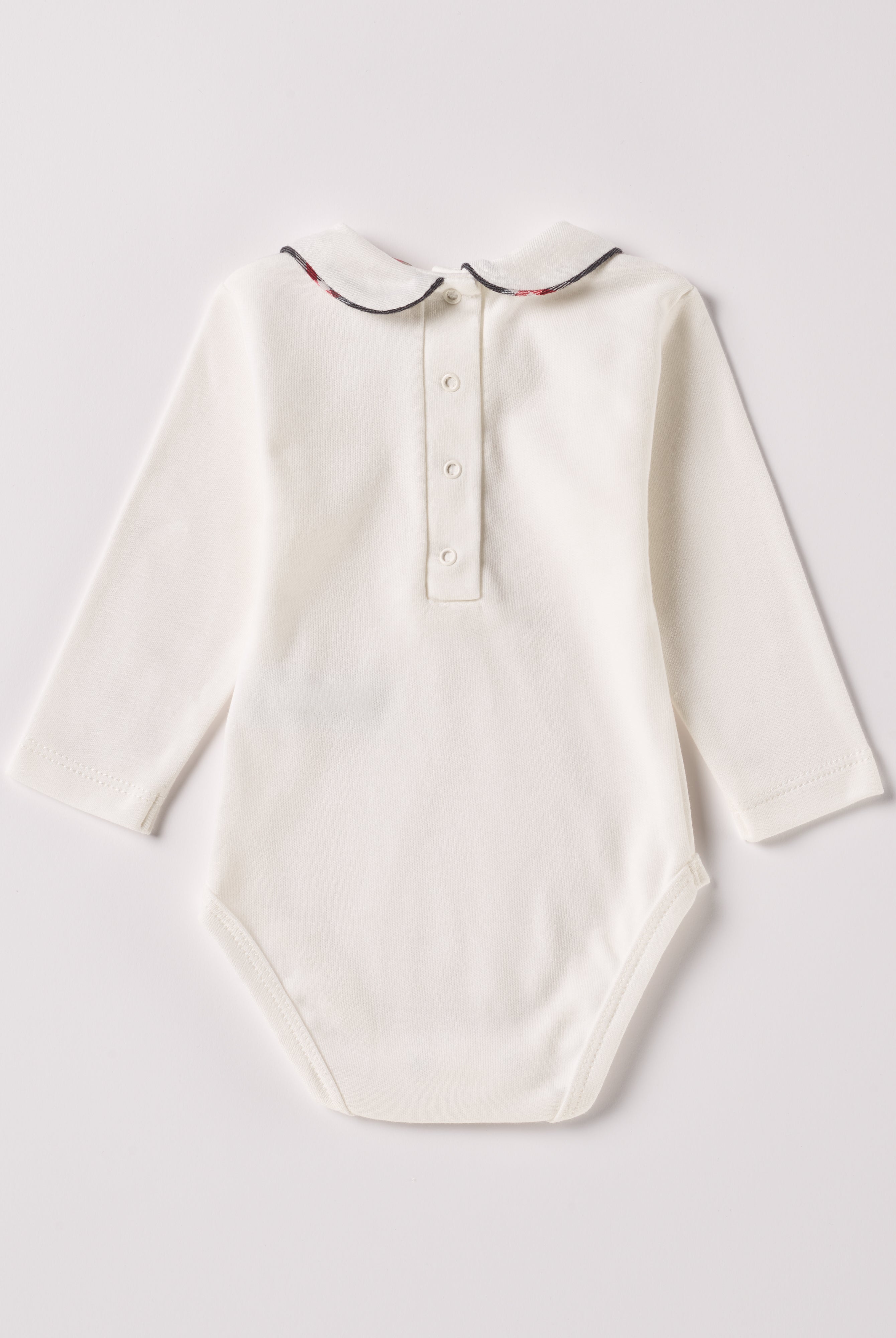 Der langarmige Body, gefertigt aus 100% Baumwolle, hat eine perfekte Passform. Kundinnen und Kunden vertrauen auf unseren Schnitt, da die flachen Knöpfe an der Rückseite ein unkompliziertes und schnelles Anziehen ermöglichen. Die "flanellartige" Innenseite wurde speziell für zarte Kinderhaut konzipiert und bietet ein besonders sanftes Trageerlebnis. Ein großer Vorteil der flanellartigen Innenseite ist, dass die Kinder weniger schwitzen. Der Kragen verleiht dem Body ein edles Design.