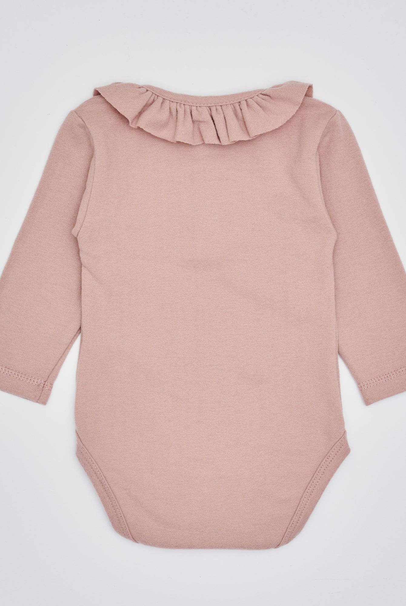Der langarmige Body hat eine perfekte Passform. Kundinnen und Kunden vertrauen auf unseren Schnitt, da die flachen Knöpfe ein unkompliziertes und schnelles Anziehen ermöglichen. Die "flanellartige" Innenseite wurde speziell für zarte Kinderhaut konzipiert und bietet ein besonders sanftes Trageerlebnis. Ein großer Vorteil der flanellartigen Innenseite ist, dass die Kinder weniger schwitzen. Der Kragen verleiht dem Body ein edles Design, sodass man diesen auch zu besonderen Anlässen tragen kann.