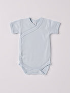 Der kurzarmige Wickelbody, gefertigt aus 100% Baumwolle, hat eine perfekte Passform. Kundinnen und Kunden vertrauen auf unseren Schnitt, da dieses Modell ein unkompliziertes und schnelles Anziehen ermöglicht. Die "flanellartige" Innenseite wurde speziell für zarte Kinderhaut konzipiert und bietet ein besonders sanftes Trageerlebnis. Ein großer Vorteil der flanellartigen Innenseite ist, dass die Kinder weniger schwitzen. Ein AMIO Firenze Must-Have für jede Grundausstattung.