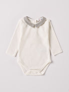 Der langarmige Body, gefertigt aus 100% Baumwolle, hat eine perfekte Passform. Kundinnen und Kunden vertrauen auf unseren Schnitt, da die flachen Knöpfe an der Rückseite ein unkompliziertes und schnelles Anziehen ermöglichen. Die "flanellartige" Innenseite wurde speziell für zarte Kinderhaut konzipiert und bietet ein besonders sanftes Trageerlebnis. Ein großer Vorteil der flanellartigen Innenseite ist, dass die Kinder weniger schwitzen. Der Kragen verleiht dem Body ein edles Design.