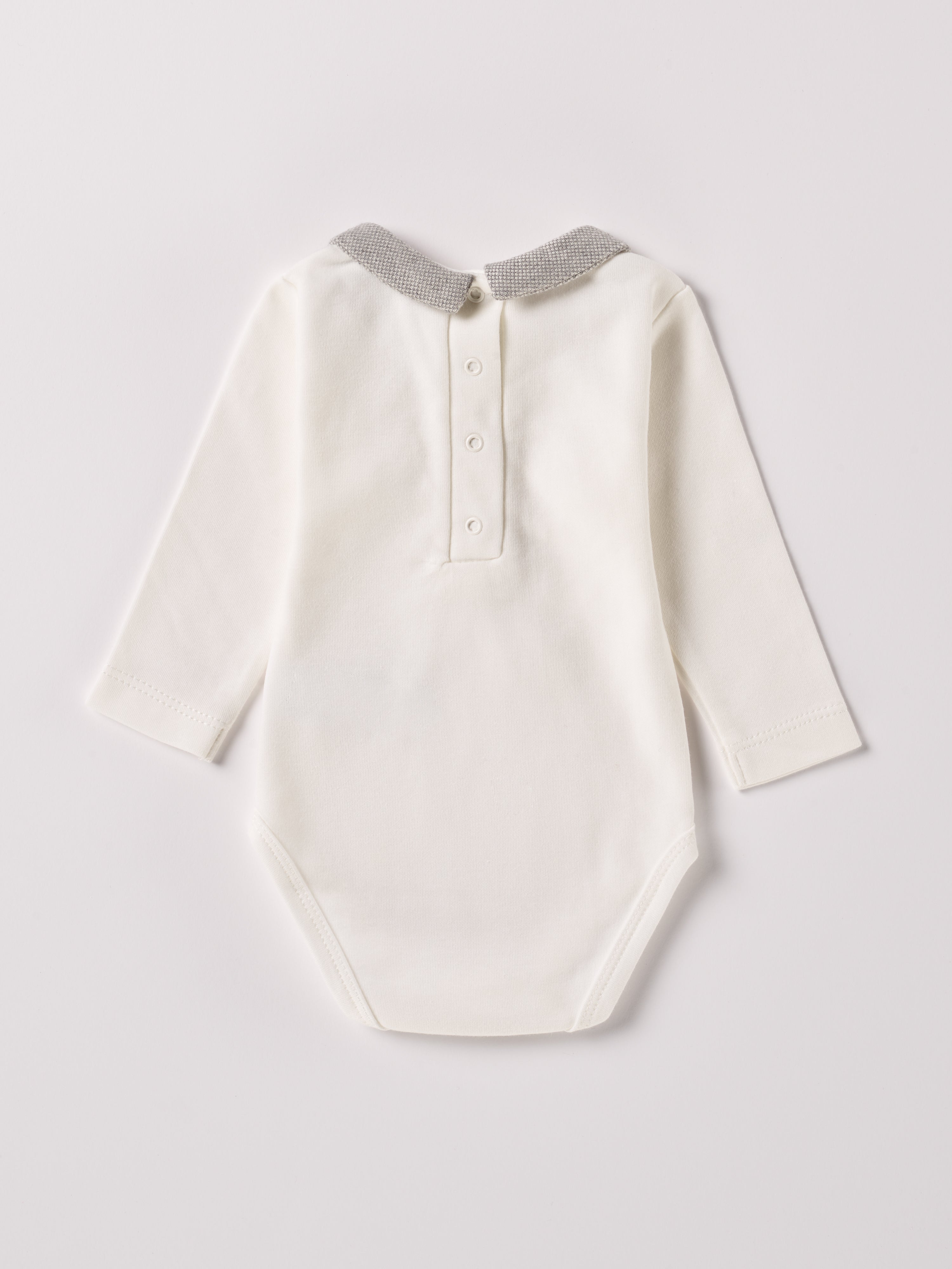 Der langarmige Body, gefertigt aus 100% Baumwolle, hat eine perfekte Passform. Kundinnen und Kunden vertrauen auf unseren Schnitt, da die flachen Knöpfe an der Rückseite ein unkompliziertes und schnelles Anziehen ermöglichen. Die "flanellartige" Innenseite wurde speziell für zarte Kinderhaut konzipiert und bietet ein besonders sanftes Trageerlebnis. Ein großer Vorteil der flanellartigen Innenseite ist, dass die Kinder weniger schwitzen. Der Kragen verleiht dem Body ein edles Design.
