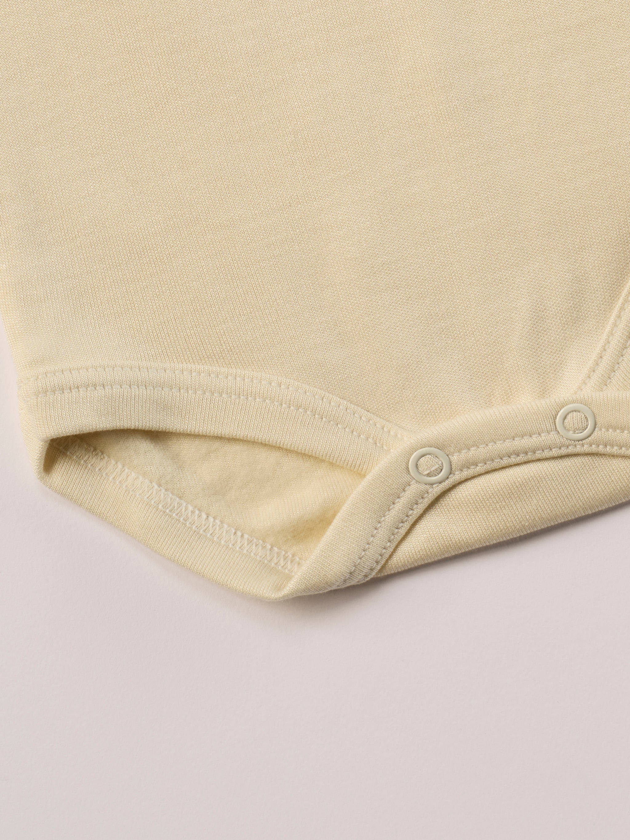 Für besonders sensible Babyhaut. Dieser beige Amerciano Body besteht aus hochwertiger Bambusviskose — einem Material, das für seine seidige Weichheit, hohe Atmungsaktivität und temperaturausgleichenden Eigenschaften bekannt ist. Sanft zur Haut, funktional im Alltag.