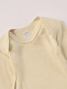 Für besonders sensible Babyhaut. Dieser beige Amerciano Body besteht aus hochwertiger Bambusviskose — einem Material, das für seine seidige Weichheit, hohe Atmungsaktivität und temperaturausgleichenden Eigenschaften bekannt ist. Sanft zur Haut, funktional im Alltag.