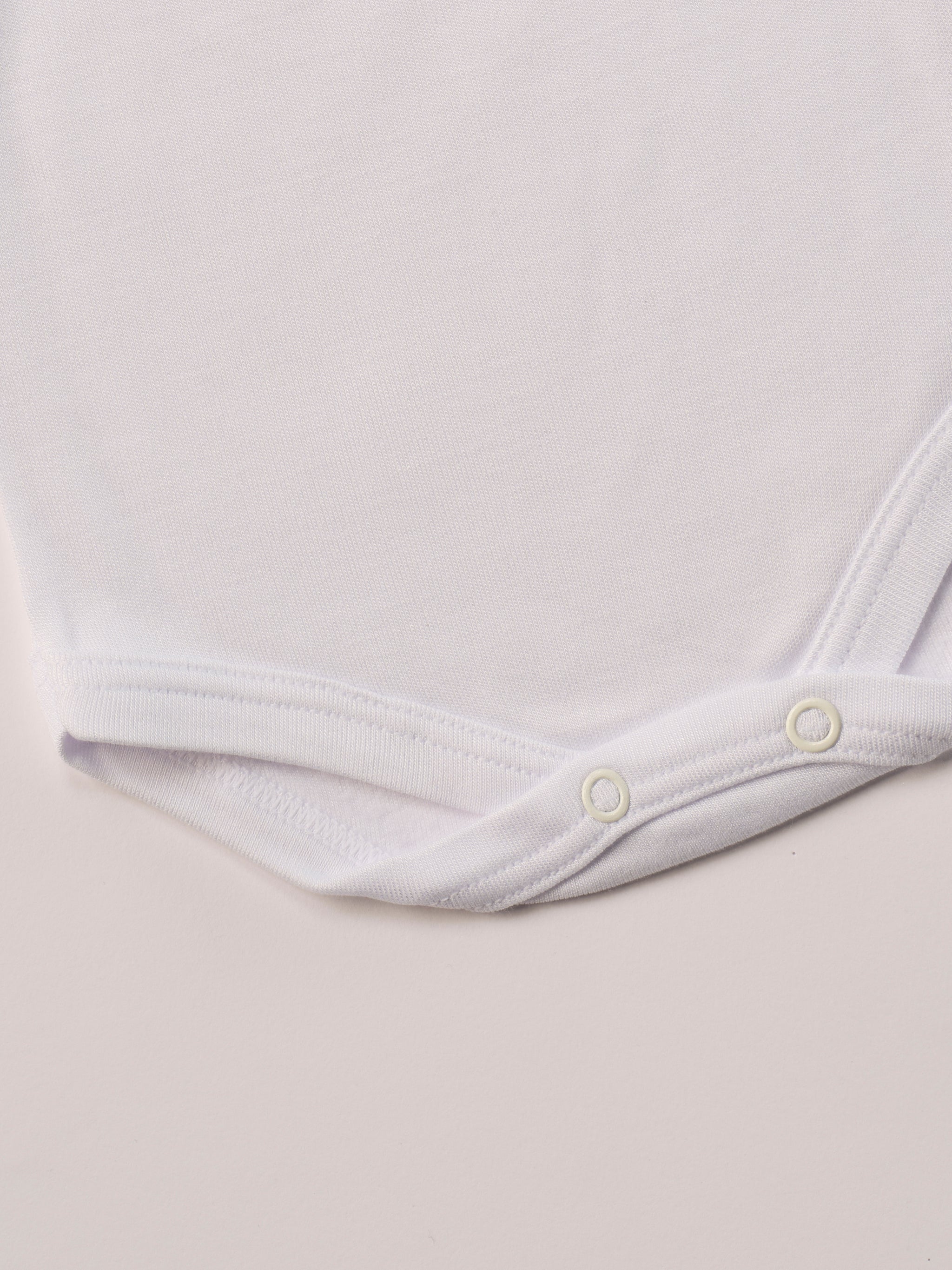 Für besonders sensible Babyhaut. Dieser weiße Amerciano Body besteht aus hochwertiger Bambusviskose — einem Material, das für seine seidige Weichheit, hohe Atmungsaktivität und temperaturausgleichenden Eigenschaften bekannt ist. Sanft zur Haut, funktional im Alltag.