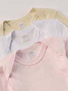 Für besonders sensible Babyhaut. Diese Amerciano Bodys in beige, weiß und rosa besteht aus hochwertiger Bambusviskose — einem Material, das für seine seidige Weichheit, hohe Atmungsaktivität und temperaturausgleichenden Eigenschaften bekannt ist. Sanft zur Haut, funktional im Alltag.
