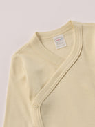 Für besonders sensible Babyhaut. Dieser beige Wickelbody besteht aus hochwertiger Bambusviskose — einem Material, das für seine seidige Weichheit, hohe Atmungsaktivität und temperaturausgleichenden Eigenschaften bekannt ist. Sanft zur Haut, funktional im Alltag.