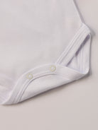 Für besonders sensible Babyhaut. Diese Wickelbodys in weiß und beige bestehen aus hochwertiger Bambusviskose — einem Material, das für seine seidige Weichheit, hohe Atmungsaktivität und temperaturausgleichenden Eigenschaften bekannt ist. Sanft zur Haut, funktional im Alltag.