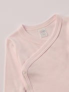Für besonders sensible Babyhaut. Dieser rosa Wickelbody für Frühchen besteht aus hochwertiger Bambusviskose — einem Material, das für seine seidige Weichheit, hohe Atmungsaktivität und temperaturausgleichenden Eigenschaften bekannt ist. Sanft zur Haut, funktional im Alltag.