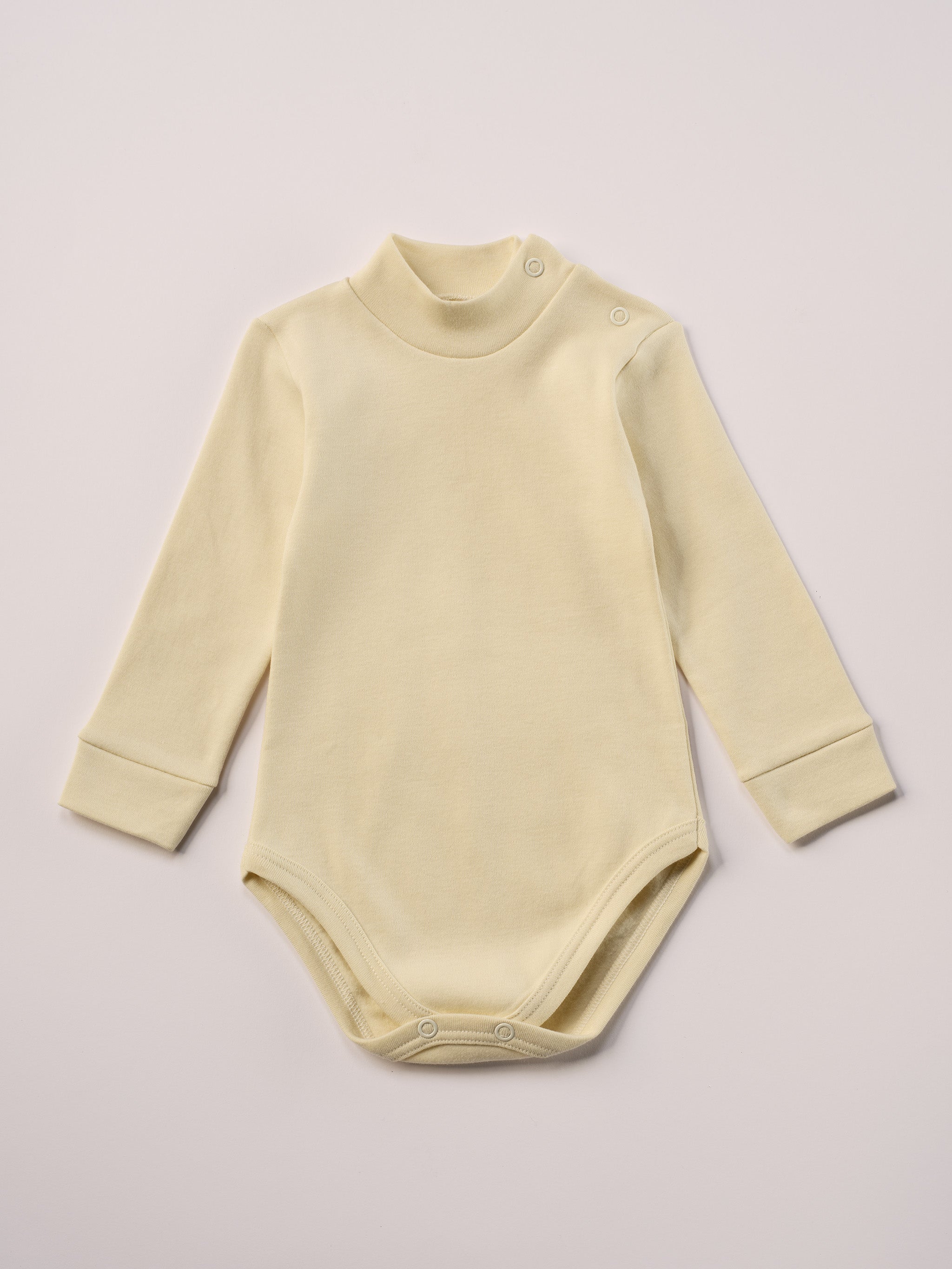 Dieser beige Stehkragenbody besteht aus hochwertiger, sorgfältig veredelter organischer Baumwolle. Die Stoffe sind sanft gefärbt und gebleicht unter Einhaltung strenger EU-Standards. Die nickelfreien Druckknöpfe an der Schulterpartie machen das An- und Ausziehen unkompliziert und schnell.

Innen sorgt die weich angeraute Oberfläche für angenehme Wärme, Feuchtigkeitsaufnahme und ein sanftes Hautgefühl. Der schützende Stehkragen hält den empfindlichen Halsbereich warm und reduziert Zugluft.