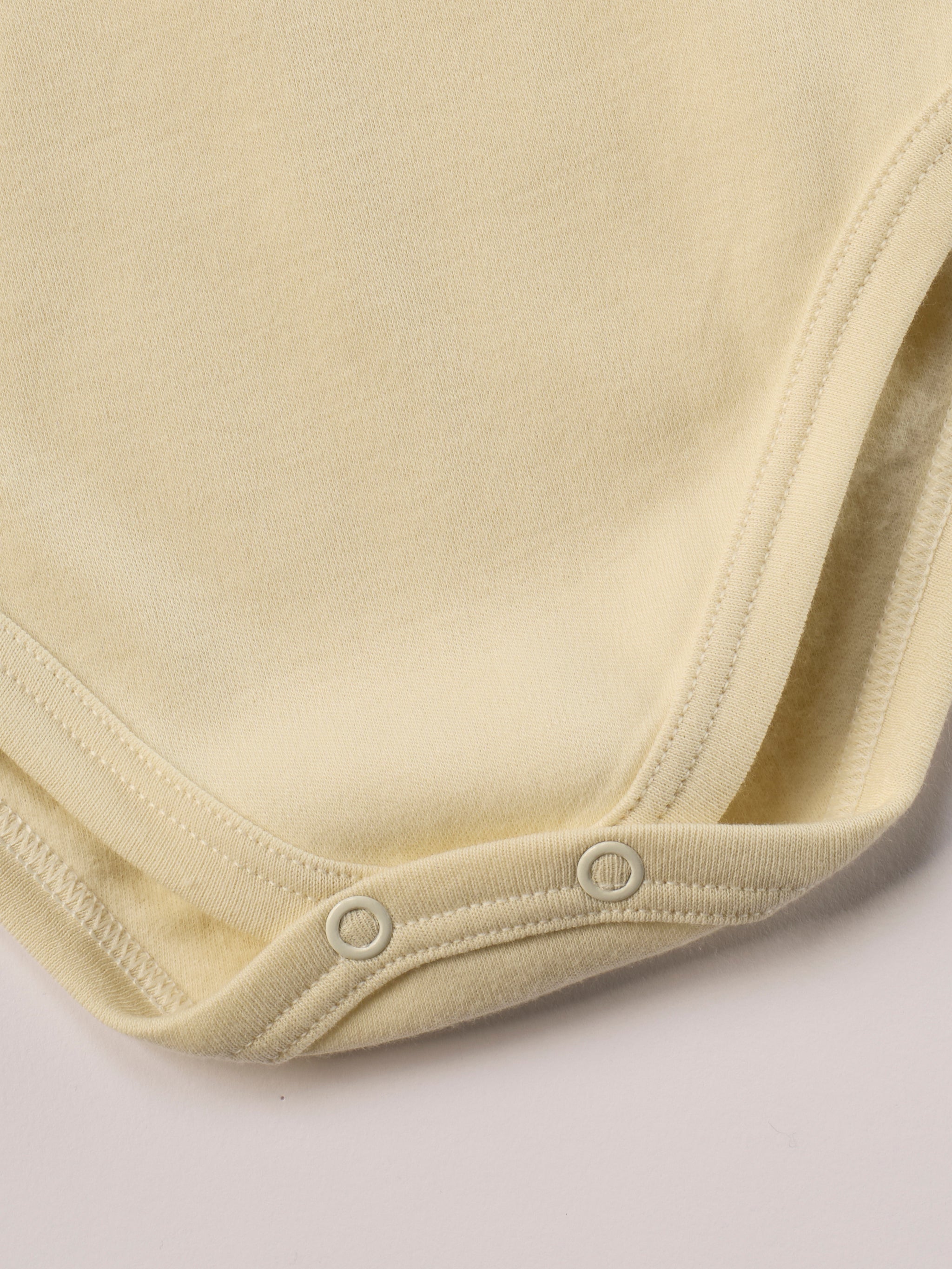 Dieser beige Stehkragenbody besteht aus hochwertiger, sorgfältig veredelter organischer Baumwolle. Die Stoffe sind sanft gefärbt und gebleicht unter Einhaltung strenger EU-Standards. Die nickelfreien Druckknöpfe an der Schulterpartie machen das An- und Ausziehen unkompliziert und schnell.

Innen sorgt die weich angeraute Oberfläche für angenehme Wärme, Feuchtigkeitsaufnahme und ein sanftes Hautgefühl. Der schützende Stehkragen hält den empfindlichen Halsbereich warm und reduziert Zugluft.