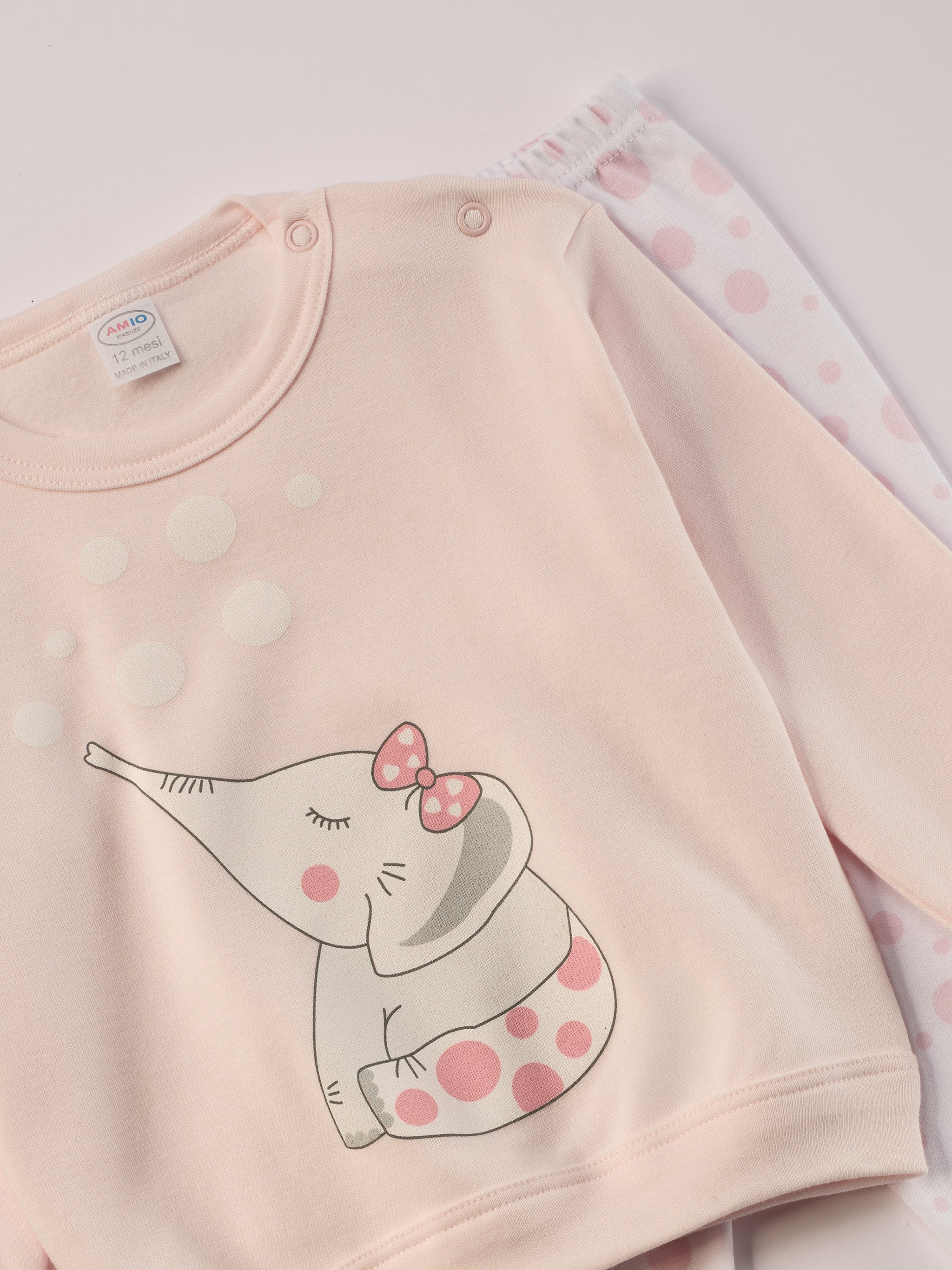Für ruhige Nächte und gemütliche Morgenstunden. Dieser Pyjama für Babys & Kinder von 12 Monaten bis 3 Jahren besteht aus hochwertiger organischer Baumwolle und ist innen sanft angeraut. Das weiche Innenflanell sorgt für ein besonders angenehmes Tragegefühl und hält warm, ohne zu überhitzen. Gefertigt in Italien aus Stoffen italienischer Produktion – mit einem klaren Anspruch an Qualität, Langlebigkeit und kindgerechtem Komfort. Design mit rosa Elefanten-Motiv auf dem Oberteil und rosa gepunkteter Hose.