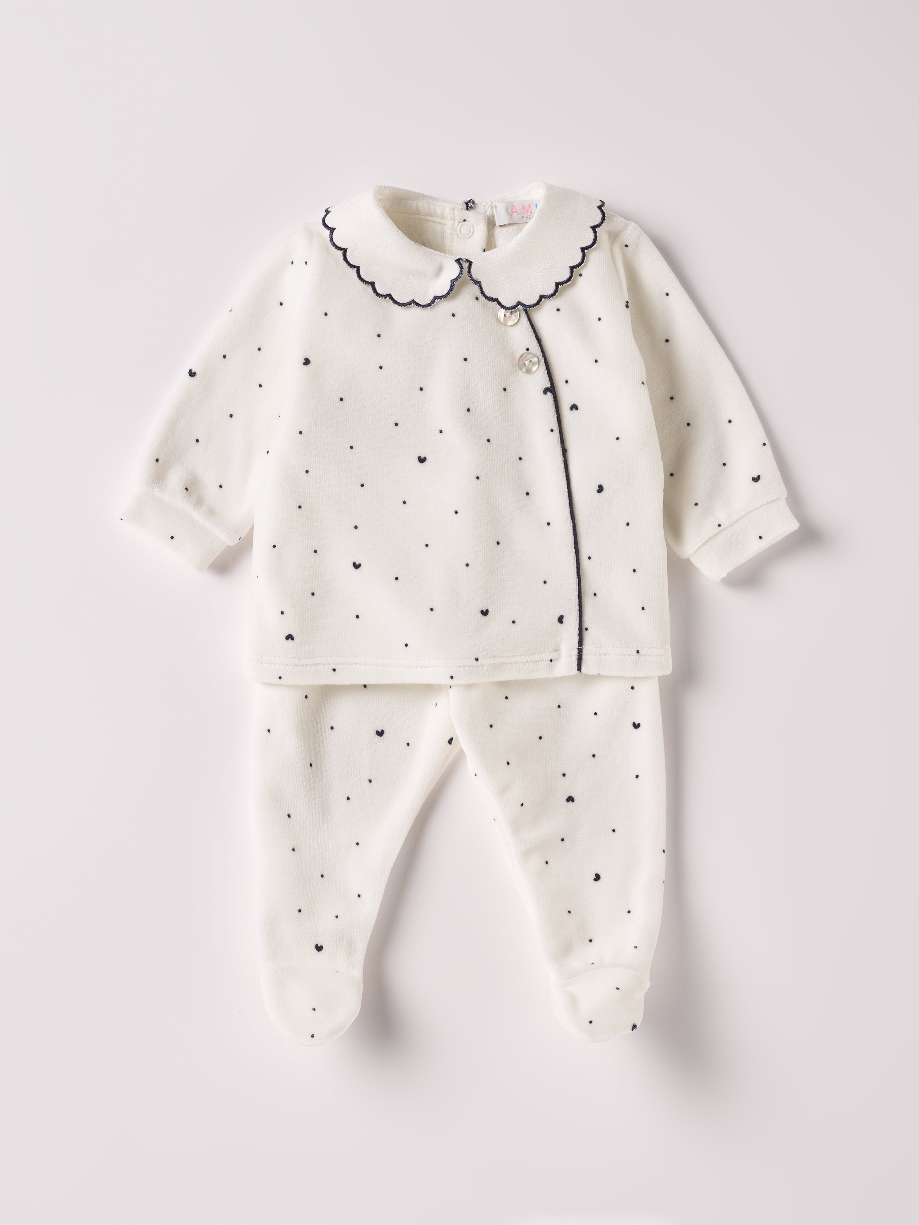 Der weiche und wärmespendende Zweiteiler von AMIO Firenze mit besticktem Kragen und eingewebten Herzen ist der perfekte Begleiter für den Alltag in der kalten Jahreszeit. Die echten Perlmuttknöpfe auf der Vorderseite veredeln den Look. Maximaler Tragekomfort, gepaart mit einer herausragenden Passform aus Samt (Ciniglia). Das Modell hat einen praktischen Schnitt, um etwa die Windel schnell und unkompliziert wechseln zu können. Das Set aus Oberteil und Hose ist vielseitig kombinierbar.