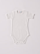 Der weiße Kurzarm-Body, gefertigt aus 70% Bambus und 30% Baumwolle, hat eine perfekte Passform. Kundinnen und Kunden vertrauen auf unseren Schnitt, da dieses Modell mit den Druckknöpfen an der Schulterpartie ein unkompliziertes und schnelles Anziehen ermöglicht. Ein großer Vorteil der Bambusfaser ist, dass sie wärmeregulierende Eigenschaften hat, sodass die Babys nicht schwitzen. Zudem ist die Bambusfaser allergikerfreundlich. Ein AMIO Firenze Must-Have für jede Grundausstattung.