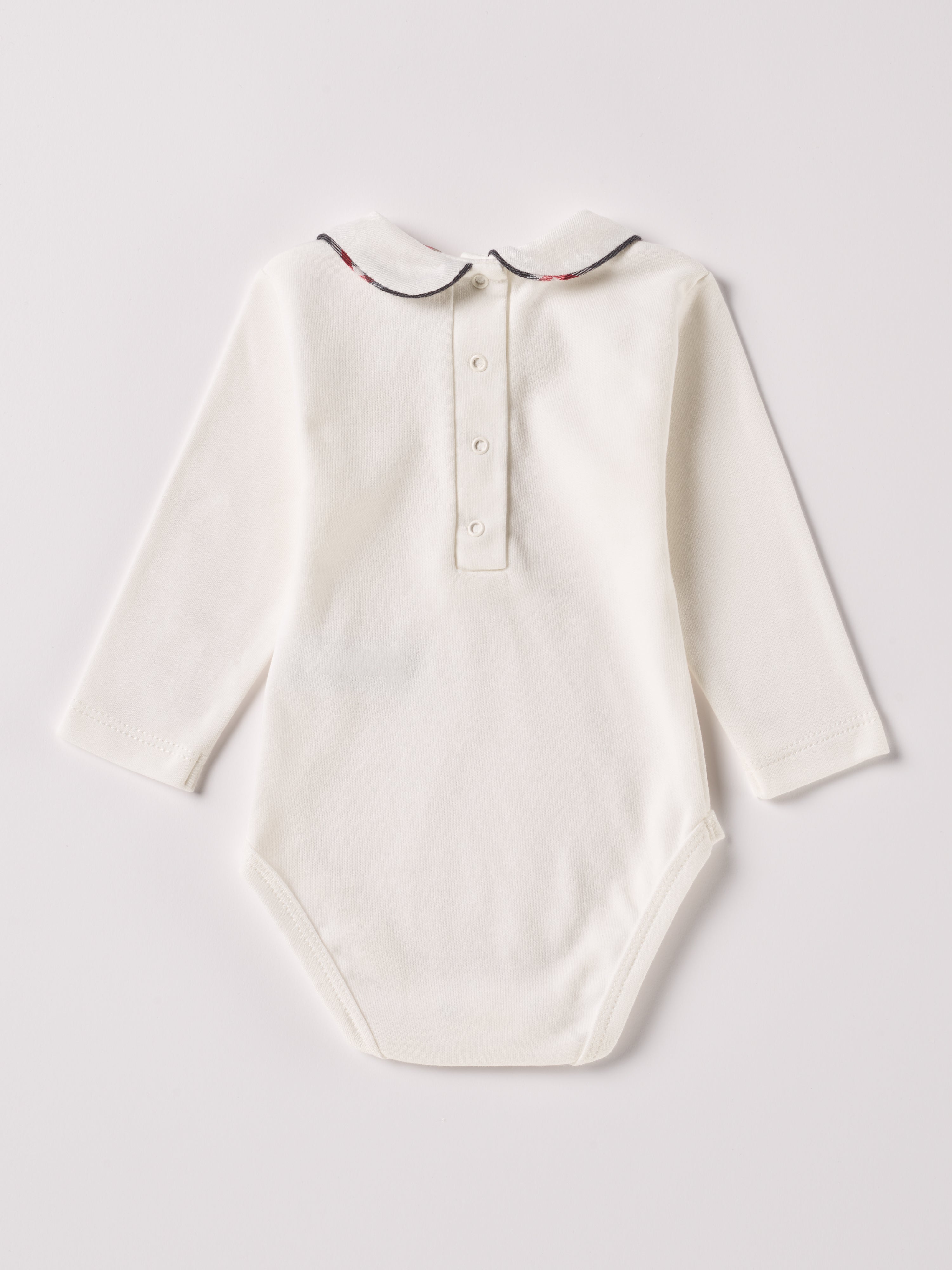 Der langarmige Body, gefertigt aus 100% Baumwolle, hat eine perfekte Passform. Kundinnen und Kunden vertrauen auf unseren Schnitt, da die flachen Knöpfe an der Rückseite ein unkompliziertes und schnelles Anziehen ermöglichen. Die "flanellartige" Innenseite wurde speziell für zarte Kinderhaut konzipiert und bietet ein besonders sanftes Trageerlebnis. Ein großer Vorteil der flanellartigen Innenseite ist, dass die Kinder weniger schwitzen. Der Kragen verleiht dem Body ein edles Design.